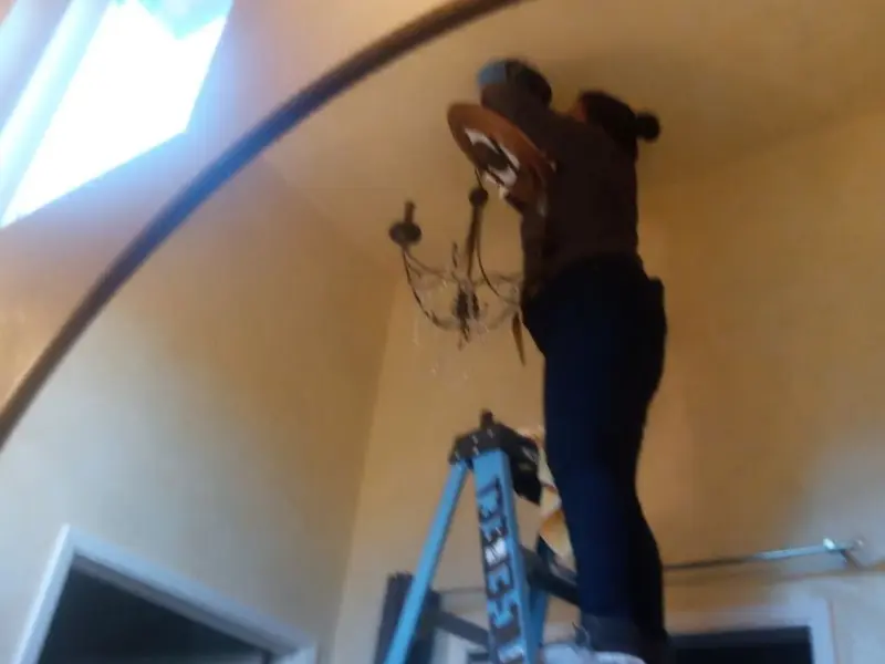Electrician installing a chandelier in a Nampa residence